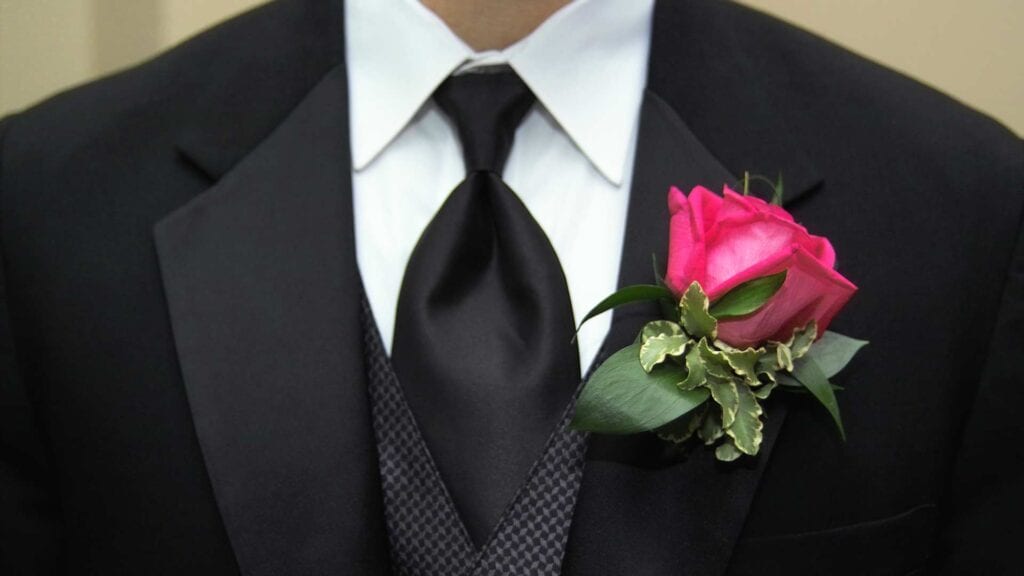 Dunkler Hochzeitsanzug mit schwarzer Krawatte und Ansteck-Blume.